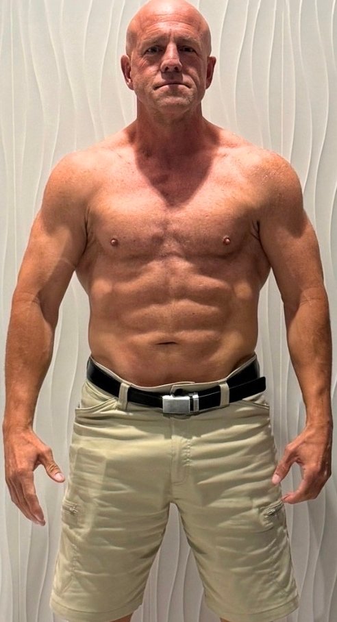 Fit older man standing shirtless with defined abdominal muscles
