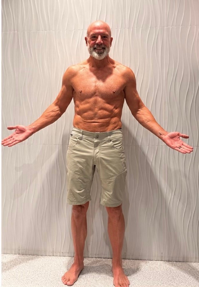 Fit older man standing shirtless with defined muscles after transformation
