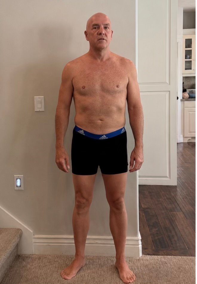 Older man standing shirtless indoors before fitness transformation