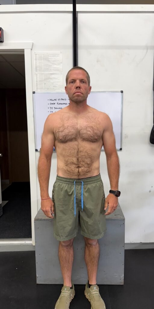 Fit man standing shirtless indoors after successful fitness transformation